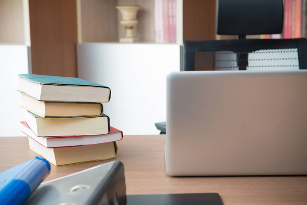 Склад книг и ноутбук на столе в офисе
 - Фото, изображение
