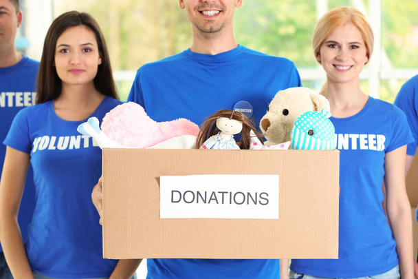 Young volunteers with box of donations indoors - Photo, Image