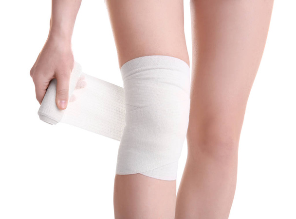 Young woman applying bandage onto leg - Фото, изображение