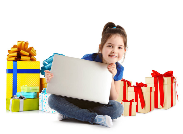 Internet shopping concept. Little girl sitting with laptop and gifts on white background - Fotó, kép