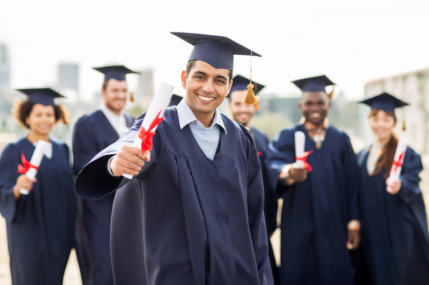 happy students in mortar boards with diplomas - Фото, изображение
