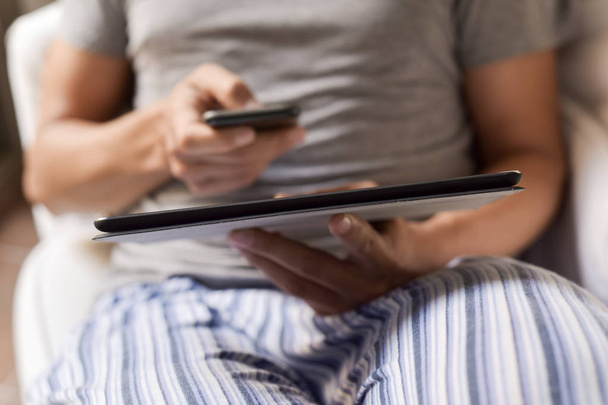 férfi pizsama egy okostelefon és a tablet használata - Fotó, kép
