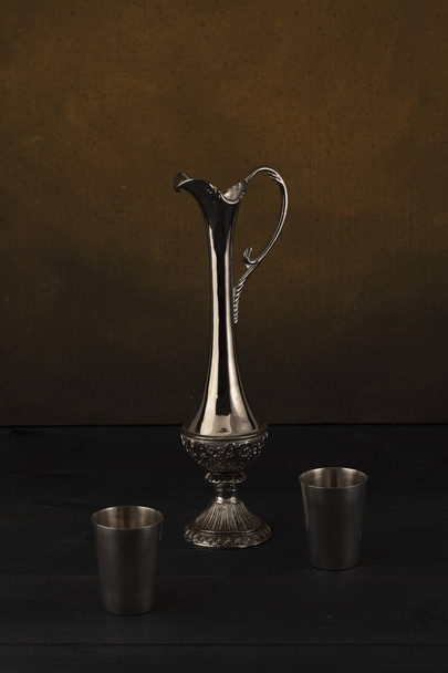 Silver jug with glasses on a dark background - Фото, зображення