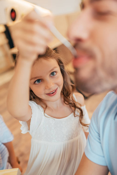 маленька дівчинка годує свого батька
 - Фото, зображення