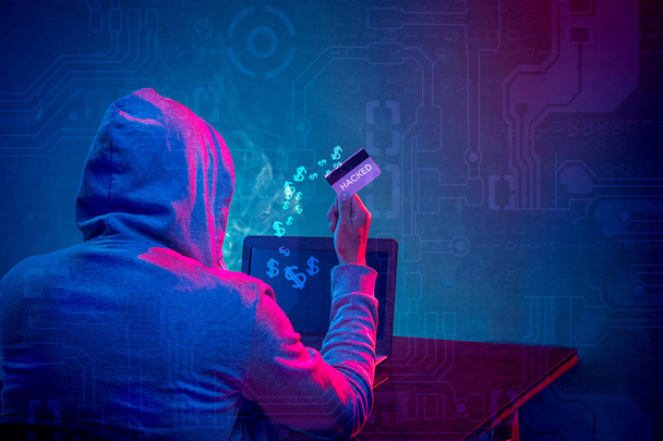 Hooded computer hacker stealing information with laptop - Fotó, kép
