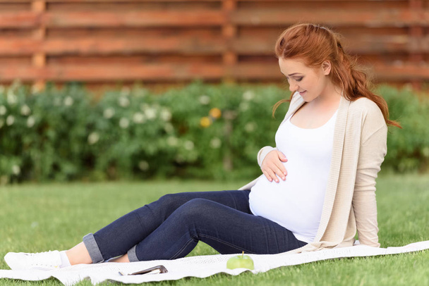 Terhes nő ül a gyep - Fotó, kép