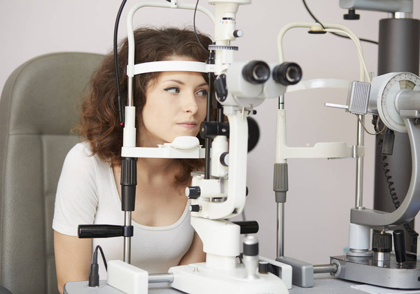 pretty young woman having her eyes examined by an eye doctor - Foto, imagen