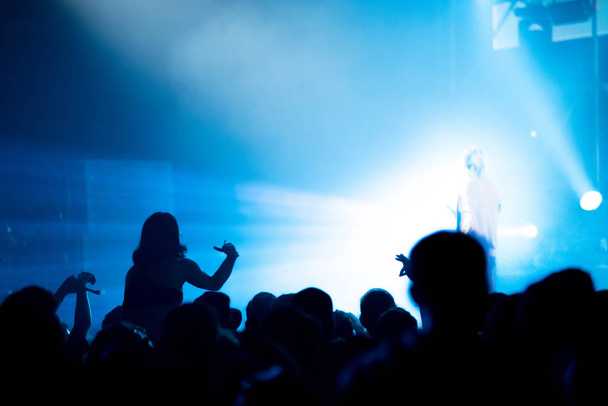 Parlak sahne ışıkları önünde konser kalabalığının silueti. - Fotoğraf, Görsel