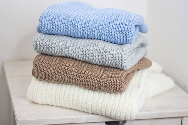 A pile of warm autumn clothing on a wooden shelf. Sweaters. Knitted winter wear. Cozy. - Foto, imagen