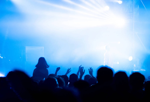Silhouette of concert crowd in front of bright stage lights - Foto, afbeelding
