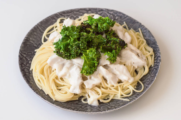 Spaghetti met gesneden kipfilet in witte roomsaus en krokante boerenkool verlaat. Evenwichtige maaltijd - Foto, afbeelding