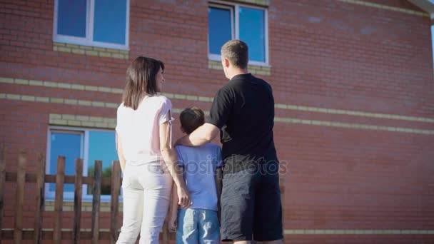 Young family with son standing outside of new house and embracing - Filmmaterial, Video