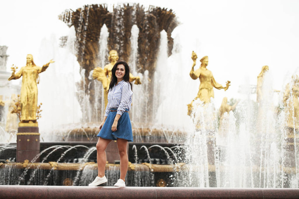Young beautiful brunette girl posing near city fountain  - Photo, Image