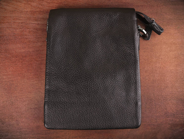 Чоловічий чорний шкіряний гаманець на дерев'яному фоні
 - Фото, зображення