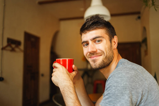 Red cup in the hands of a smiling Handsome - 写真・画像