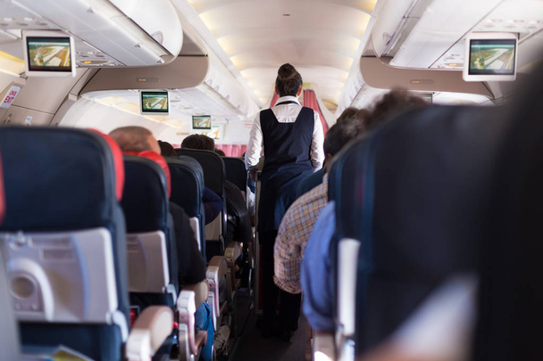 Інтер'єр комерційного літака з пасажирами на місцях під час польоту
. - Фото, зображення