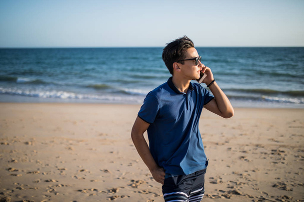 Young asian man  talking on phone and see the sunset on tropical - Photo, Image