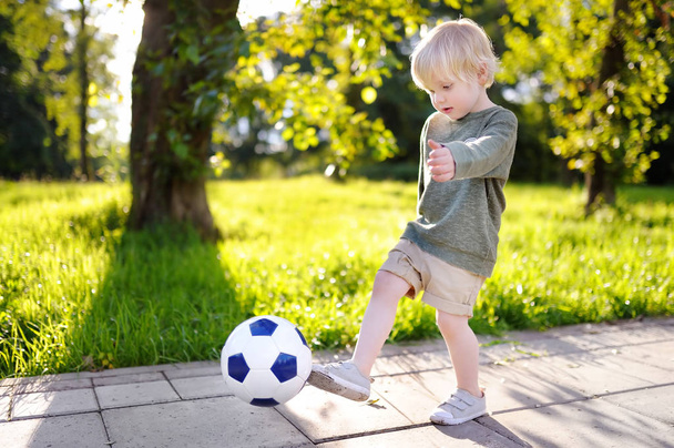 Little boy having fun playing a soccer game on sunny summer day - 写真・画像