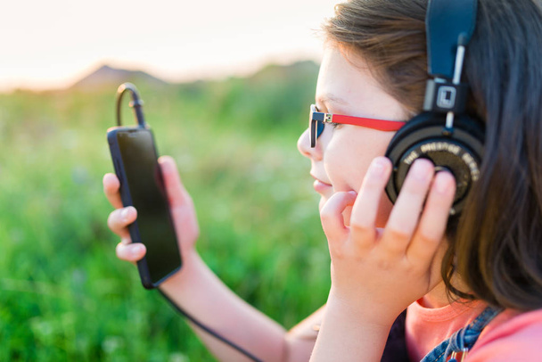Dospívající dívka poslechu hudby s její sluchátka venkovní - Fotografie, Obrázek