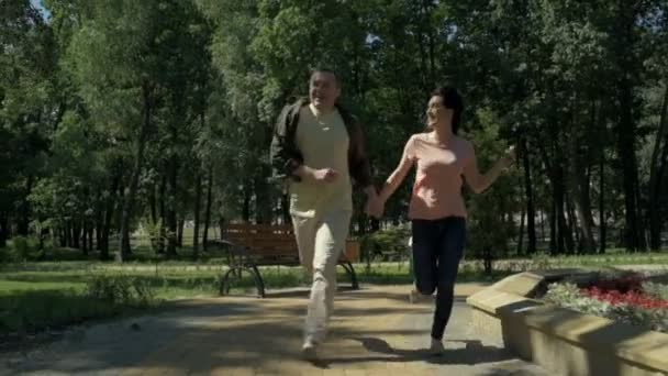 Joyful couple running in the park - Кадри, відео