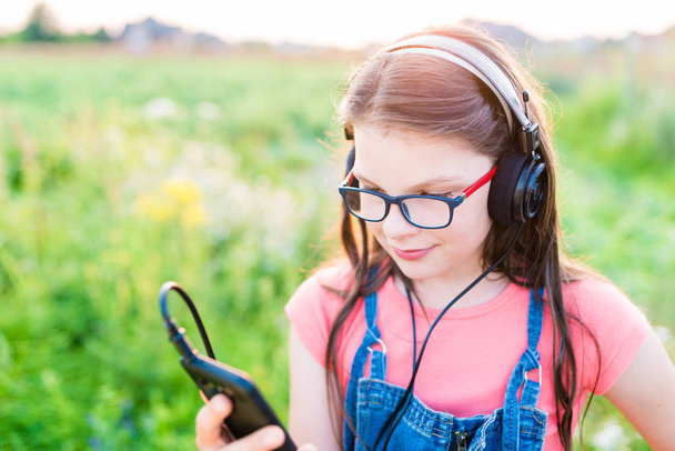 Teini tyttö kuuntelee musiikkia hänen kuulokkeet ulkona
 - Valokuva, kuva