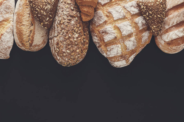 Bakery concept. Plenty of bread background isolated on balck - Φωτογραφία, εικόνα