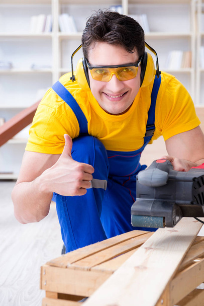 Carpintero reparador puliendo una tabla de madera con un po eléctrico - Foto, Imagen