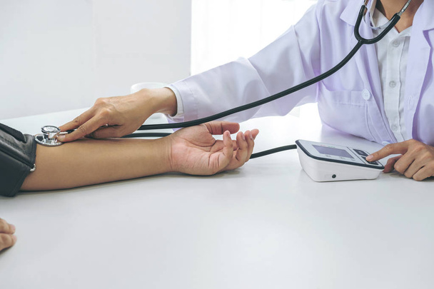 Competent attentive doctor being measuring blood pressure to patient, hospital and medicine concept. - Фото, зображення