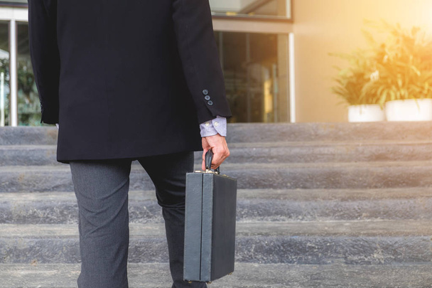 Businessman walking up the stairs and holding a briefcase in hand working with confidence. - Foto, Imagem