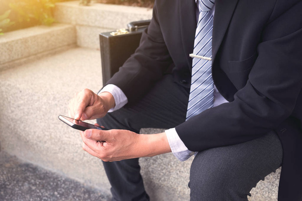 Attractive Confident businessman sitting in a black suit and usi - Φωτογραφία, εικόνα