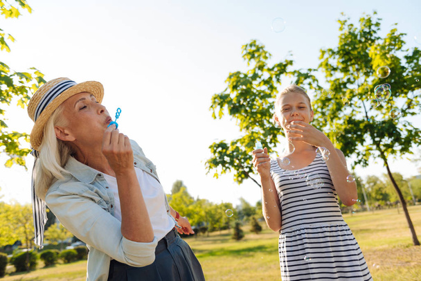 woman blowing soap bubbles with her granddaughter - Foto, afbeelding