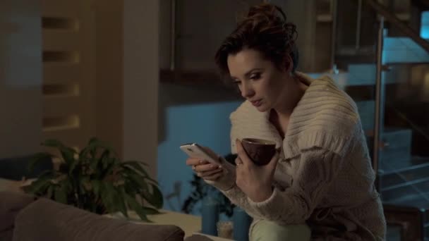 Late evening at home. Beautiful woman using smartphone - Felvétel, videó