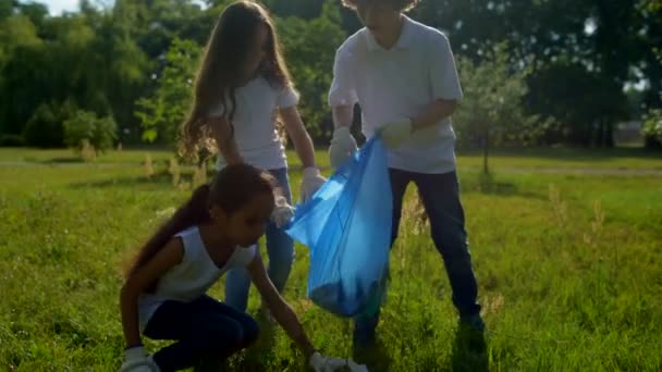 Pequeños voluntarios poniendo basura en la bolsa de basura
 - Imágenes, Vídeo