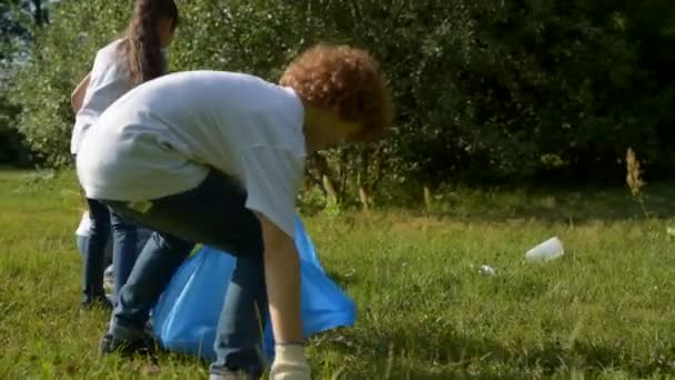 Mindful young volunteers cleaning local park area - Filmati, video