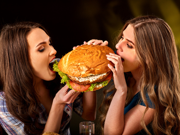Mujeres comiendo comida rápida. Gils comer hamburguesa con jamón
 . - Foto, Imagen