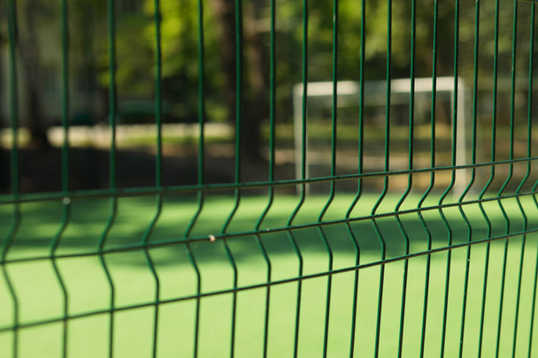 Soft focus, abstract football field with fence on foreground - Foto, imagen