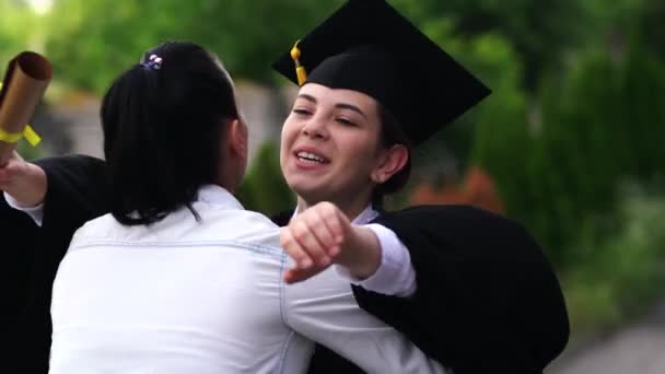 Scena all'aperto di bella studentessa laureata vestita in tazza e abito, abbracciando i suoi genitori
. - Filmati, video