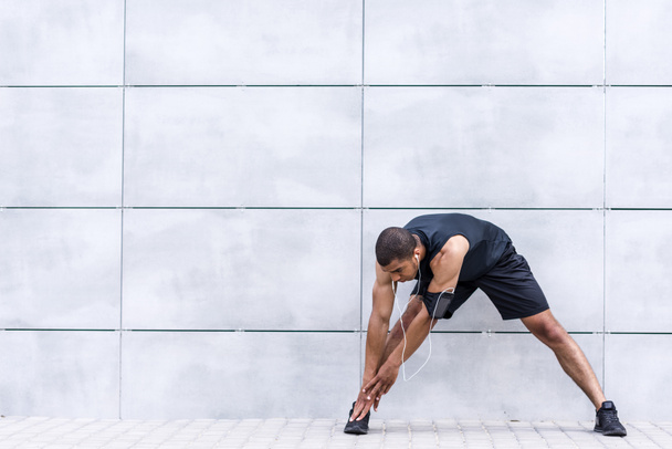 african american runner stretching on street - Photo, Image