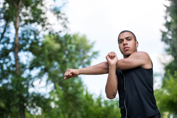 afro-amerikai sportoló, nyújtás a park  - Fotó, kép
