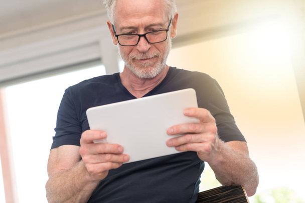 Mature man using digital tablet, light effect - Foto, afbeelding