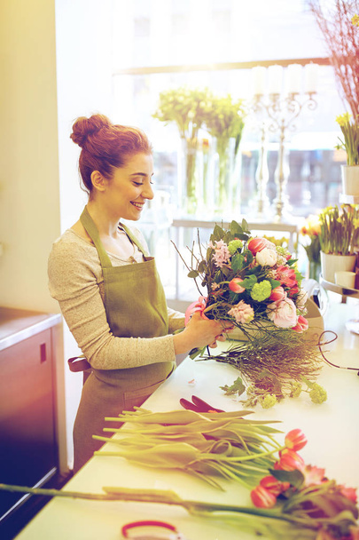 smiling florist woman making bunch at flower shop - Фото, зображення