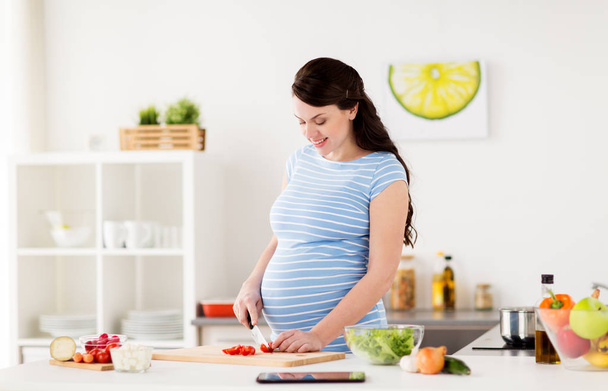 pregnant woman cooking vegetables at home - Foto, imagen