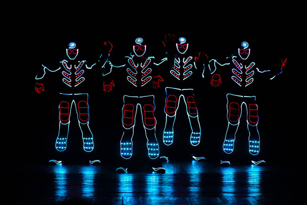 Tänzer in LED-Anzügen auf dunklem Hintergrund, farbige Show - Foto, Bild