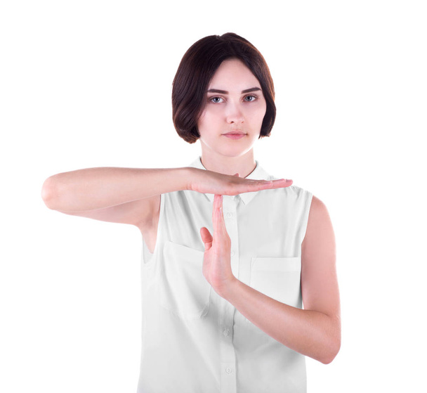 Un retrato de una joven mostrando un gesto de "tiempo fuera". Una chica con una actitud aislada sobre un fondo blanco. Una señal de ruptura
. - Foto, Imagen