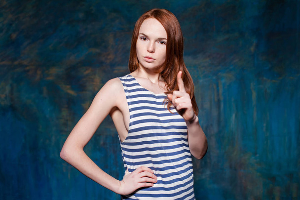 Strict redhead girl shows finger with arms akimbo - Zdjęcie, obraz