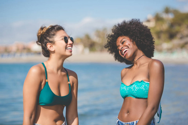 Two young female friends at seaside laughing - Foto, afbeelding