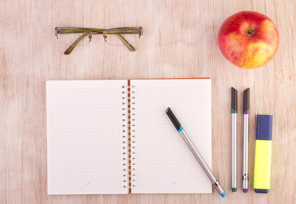 Open notebook with pencils, glasses and apple on desk - Foto, Imagen