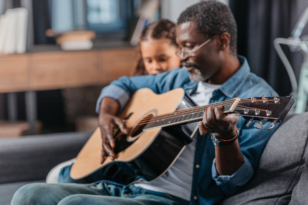 man playing guitar with daughter at home - Foto, Bild