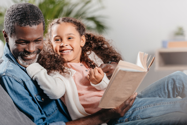 Mann liest Buch mit Tochter zu Hause - Foto, Bild