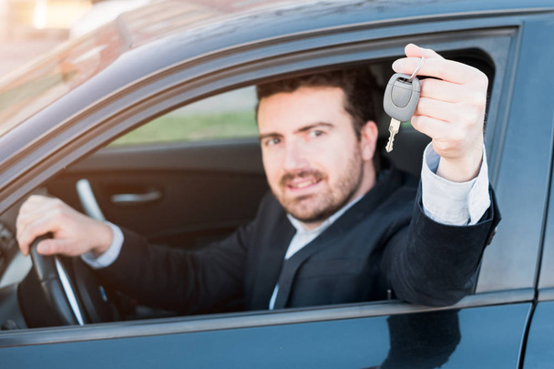 glücklicher Mann lächelt im Auto sitzend und hält Schlüssel in der Hand - Foto, Bild